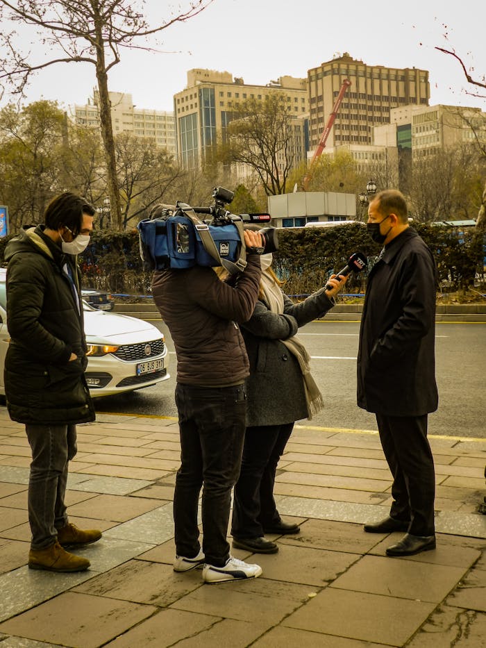 Outdoor street interview scene with journalists capturing a news event.